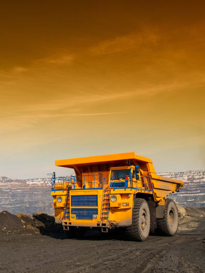 A construction vehicle travels on a dirt-covered road.